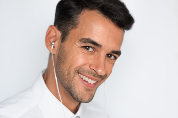 Obraz premium Close-up portrait of handsome caucasian young man enjoying his favorite music. Happy stylish smiling man in headphones against gray background. 