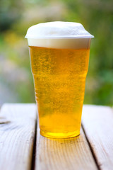 Glass of beer with foam on a wooden table on  background of natu