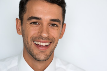 Obraz premium Portrait of young attractive man with great smile wearing white shirt on gray neutral background.