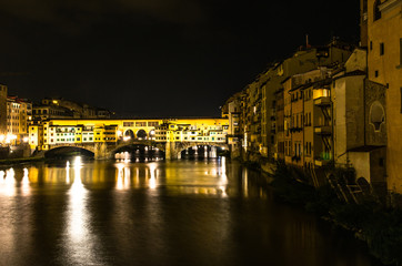 Fototapeta na wymiar Light reflection on the Arno Rive and Ponte Vecchio bridge by night, Florence