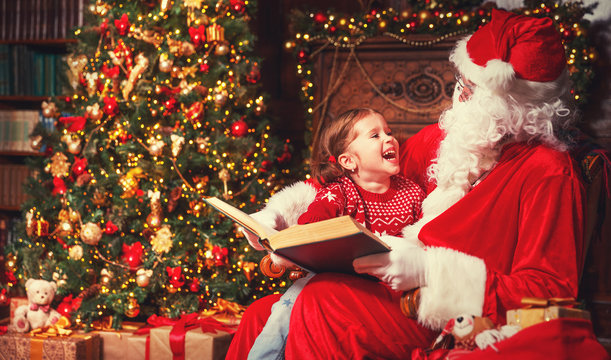 happy child girl with Santa reading book
