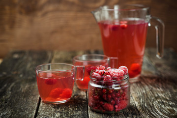 Berries compote in glass jar , two cup on wooden background. Selective focus.