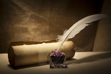 Literature concept. Old inkstand with feather near scroll on canvas background