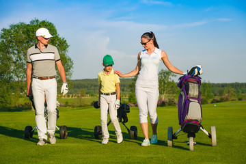 Family golfers walking on golf course at sunny day