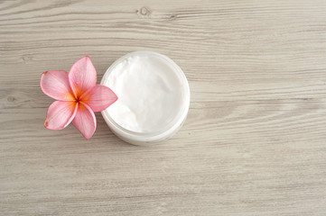 Fototapeta na wymiar Body lotion in a container with a pink frangipani flower