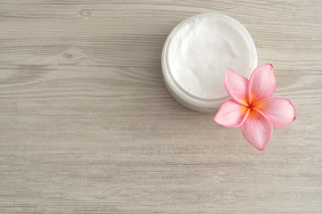 Body lotion in a container with a pink frangipani flower