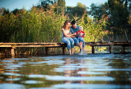 Family, mother, father and child playing and spending time with his young son in the summer the river or lake