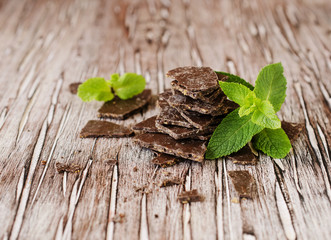 pieces of chocolate with mint on wooden background, selective focus