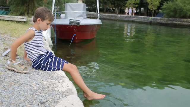 Boy tries water by feet. Video clip.
