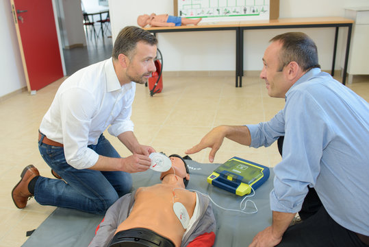 Men training to use defibrillator