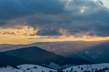 Fototapeta premium Winter sunset in the mountains. Multi-colored clouds, illuminated by the sun.