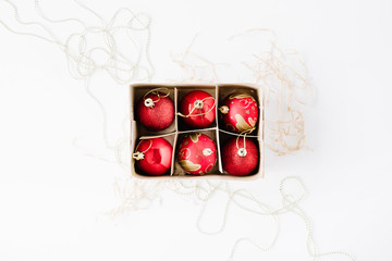 box with bright red christmas balls on white background. flat lay, top view