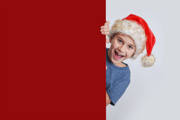 Kind mit Weihnachtsmütze hinter Wand