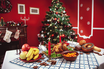 Christmas dinner by candlelight, table setting. Thanksgiving table with baked turkey in a decorated room with a Christmas tree.
