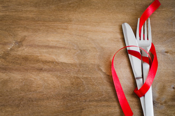 Fototapeta premium Cutlery Decorated with Red Ribbon on Wooden Background.
