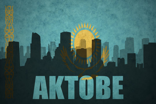 abstract silhouette of the city with text Aktobe at the vintage kazakhstan flag