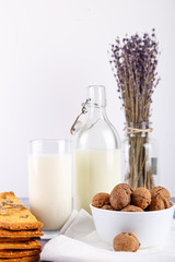 fresh healthy milk, cookies with raisins, walnuts, bunch of dry cut lavender on white background. selective focus.