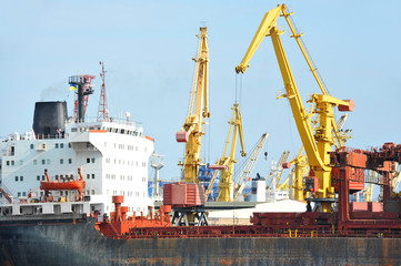 Obraz premium Bulk cargo ship under port crane