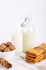 fresh healthy milk, cookies with raisins, walnuts, cinnamon sticks on white background. selective focus.