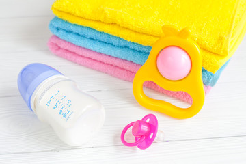 baby bottle with milk and towel on wooden background