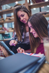 Two young female college students doing research in library