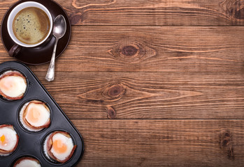 Fototapeta na wymiar Breakfast baked eggs with bacon in muffin tin. Cup of coffe.