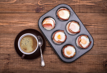 Breakfast baked eggs with bacon  in muffin tin. Cup of coffe.