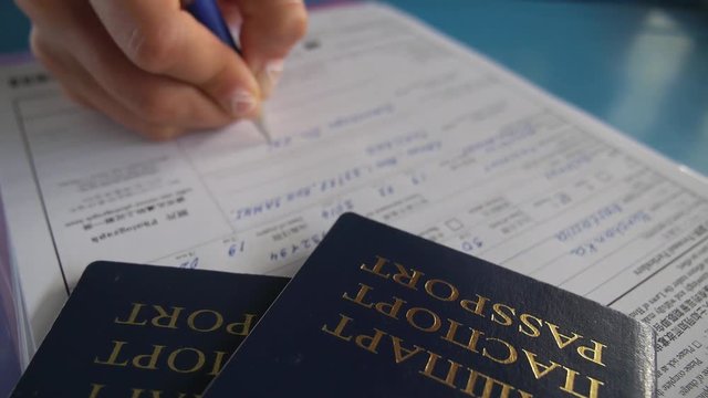Female Hand Fills Customs Declaration with Travel Passport