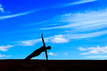 Silhouette of woman practicing yoga at sunlight