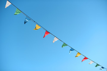 Guirnaldas de fiesta coloridas colgando en la calle en un día soleado con un cielo azul despejado