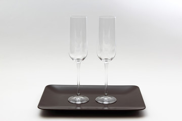 two empty wine glass on a brown plate on light background