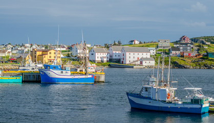 Fototapeta na wymiar Bona Vista, Newfoundland fishing village. Boats tied up - in for the day, bright sunshine on calm coastal water.