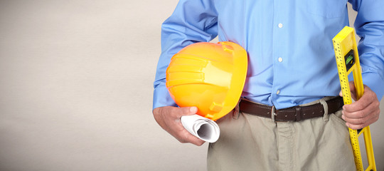 Hands of construction worker with helmet and level.