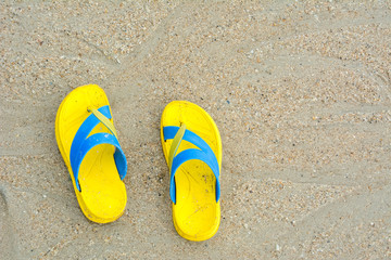 Fototapeta premium Yellow sandals on sandy beach