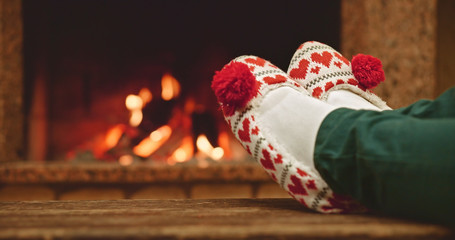 Woman relaxes by warm fire with a cup of hot drink and wriggles