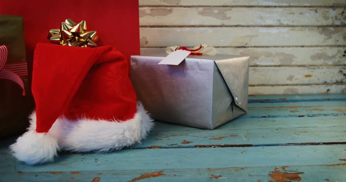 Wrapped gifts and santa hat on wooden plank
