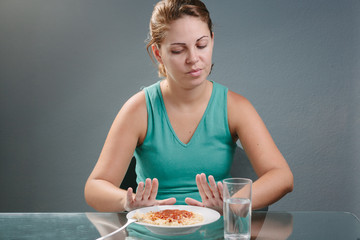 Portrait of woman with no appetite in front of the meal. Concept of loss of appetite