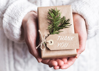Hands holding hand crafted gift with label, text Thank You.
