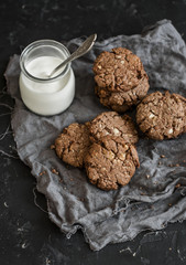 Gluten free chocolate cookies with walnuts and a jar of yogurt on a dark background