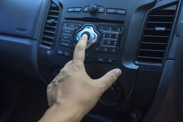 Hand pushing the power button on a car.