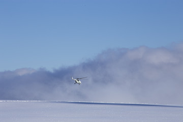 Helicopter over the snowy plain on a background of clouds