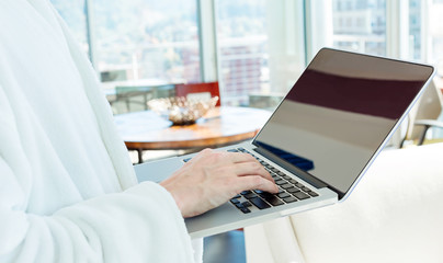 Man in a bathrobe on a laptop in a bright room