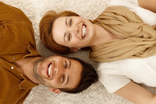 Happy couple lying on carpet side by side