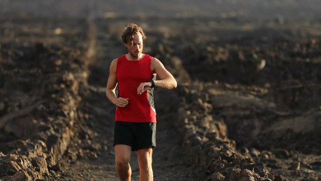 Runner looking at heart rate monitor activity tracker smartwatch starting run. Active athlete looking at his running watch using app after cardio workout for pace and distance information. 59.94 FPS.