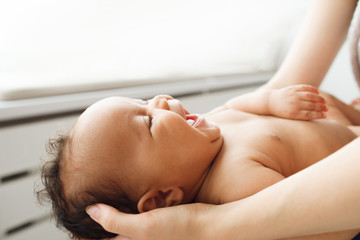Laughing newborn baby on mother hands, free space for text. Mom holding happy smiling adorable kid....