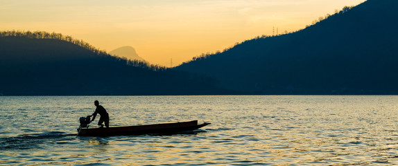 silhouette of a man are boating in the dam on the morning. © TNPP Studio
