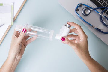 Female hands inserting an aerosol inhaler into a space chamber