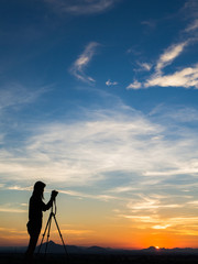 Girl photographer with camera at sunset