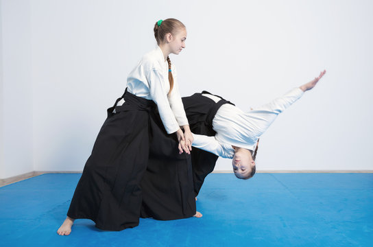 Two girls in black hakama practice Aikido on martial arts training