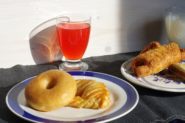 breakfast with donuts, salty croissant, fruit juice and milk